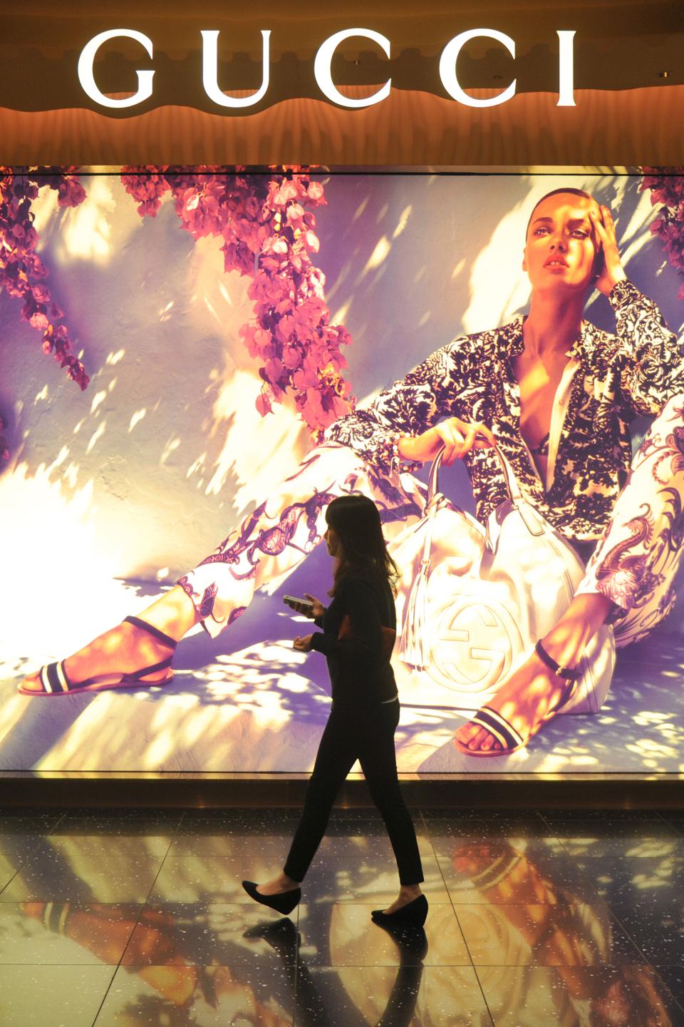 A woman walks past a large Gucci adverti