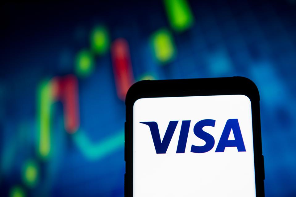 In this photo illustration a VISA logo seen displayed on a...